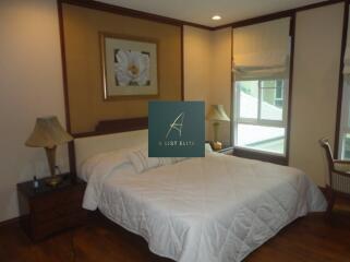 Spacious bedroom with a large bed, bedside tables, and a window with a view.