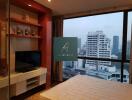 Bedroom with a view of the city skyline, featuring a TV and a comfortable bed