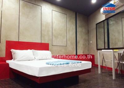 Modern bedroom with a red themed bed and wall-mounted amenities