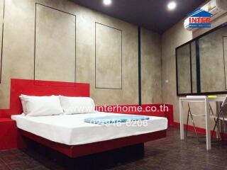 Modern bedroom with a red themed bed and wall-mounted amenities