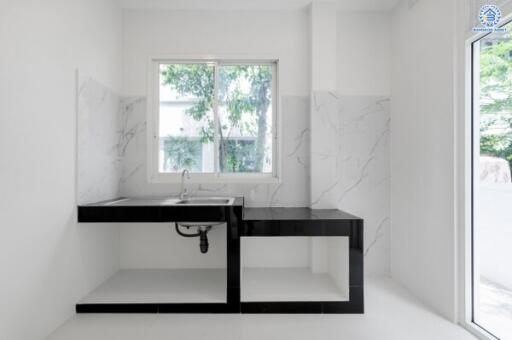 Minimalist kitchen with window, sink, and marble backsplash