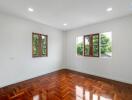 Spacious bedroom with wooden flooring and large windows