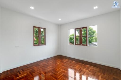 Spacious bedroom with wooden flooring and large windows