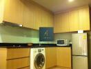 Modern kitchen with cabinets, washing machine, microwave and refrigerator