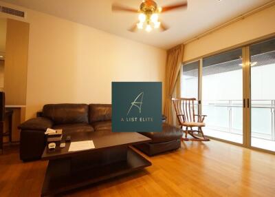 Spacious living room with wood flooring, leather sofa, coffee table, ceiling fan, and large sliding glass doors leading to a balcony.