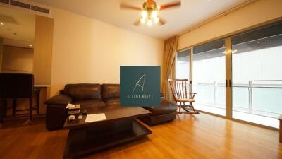 Spacious living room with wood flooring, leather sofa, coffee table, ceiling fan, and large sliding glass doors leading to a balcony.