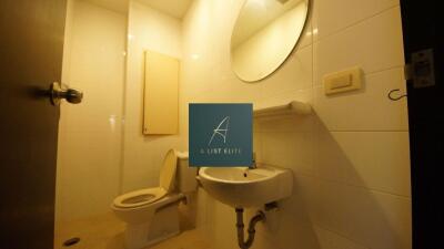 Bathroom with a circular mirror, toilet, and sink