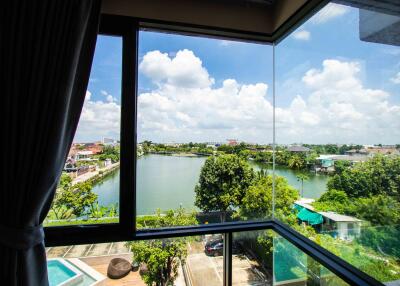 View from a window overlooking a lake with trees and buildings in the background