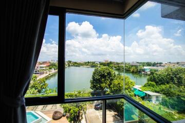 View from a window overlooking a lake with trees and buildings in the background