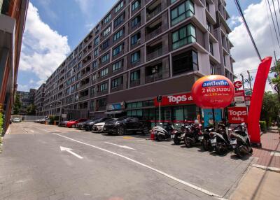 Exterior view of a multi-story residential building with a grocery store and parking area