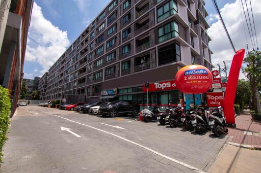 Exterior view of a multi-story residential building with a grocery store and parking area