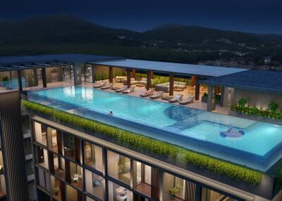 Rooftop infinity pool at night with lounge chairs and scenic mountain view