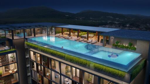 Rooftop infinity pool at night with lounge chairs and scenic mountain view