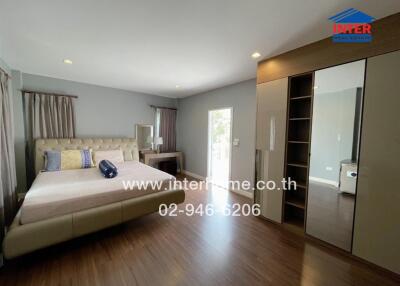 Spacious bedroom with a large bed, wooden floor, and wardrobe