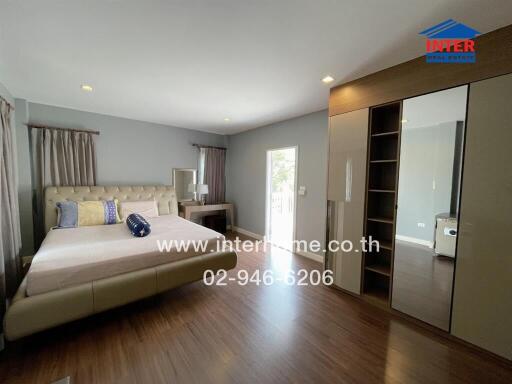 Spacious bedroom with a large bed, wooden floor, and wardrobe