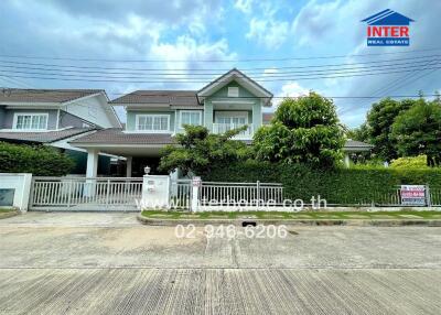 Front view of a modern two-story house with a well-maintained garden and driveway