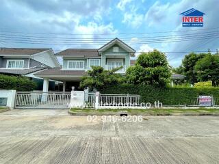 Front view of a modern two-story house with a well-maintained garden and driveway