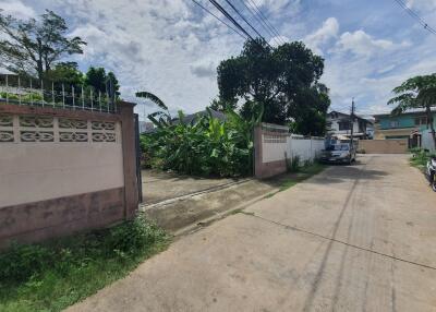 Driveway leading to a building with fenced boundaries and greenery