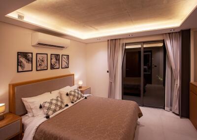 Modern bedroom with ambient lighting, wall-mounted air conditioner, and sliding glass door leading to balcony