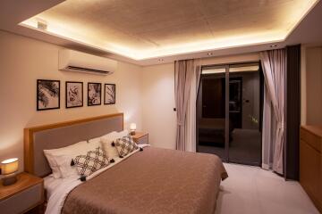 Modern bedroom with ambient lighting, wall-mounted air conditioner, and sliding glass door leading to balcony