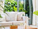 Modern living room with large glass doors, neutral sofa, wooden coffee table, and greenery outside