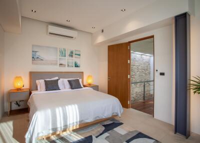 Cozy modern bedroom with bed, nightstands, wall-mounted air conditioner, artwork, and a door leading to a balcony