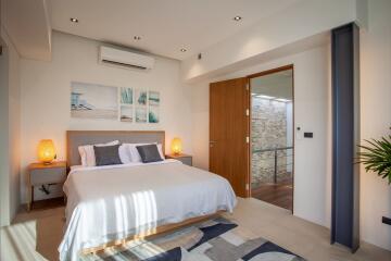 Cozy modern bedroom with bed, nightstands, wall-mounted air conditioner, artwork, and a door leading to a balcony