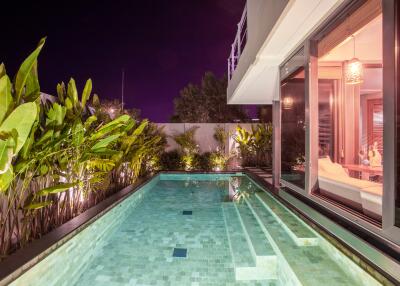 Luxurious poolside area at night with modern lighting and greenery