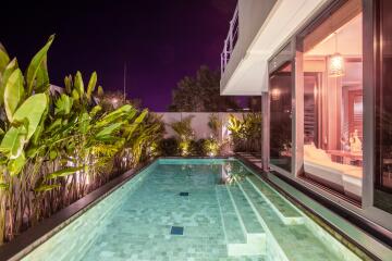 Luxurious poolside area at night with modern lighting and greenery