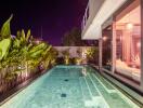 Luxurious poolside area at night with modern lighting and greenery