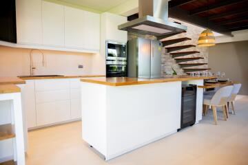 Modern kitchen with island, built-in appliances, and floating stairs