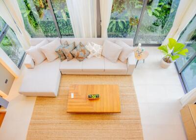 Top view of a modern living room with a large sectional sofa, coffee table, and large windows