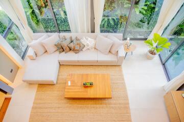 Top view of a modern living room with a large sectional sofa, coffee table, and large windows