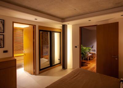 Bedroom with open doors to a lit hallway and bathroom