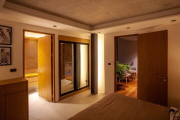 Bedroom with open doors to a lit hallway and bathroom