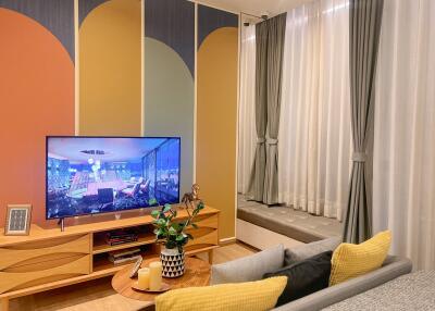 Cozy living room with wall-mounted TV, modern art paneling, large curtains, and a built-in window seat.