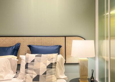 Cozy bedroom with stylish decor, blue cushions, bedside lamp, and abstract-patterned pillows