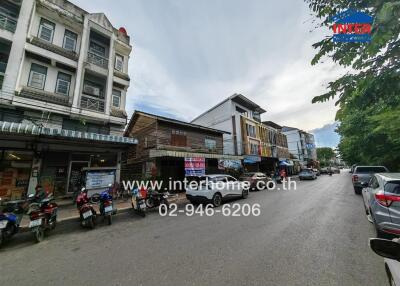 Street view of multiple buildings with shops and motorbikes parked