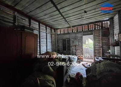 Dimly lit bedroom with wooden walls and ceiling, furnished with a wardrobe, bed, and balcony access