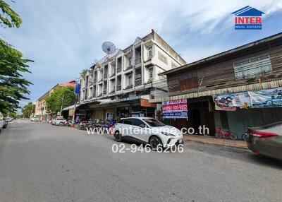 Street view of a mixed-use building with parked vehicles