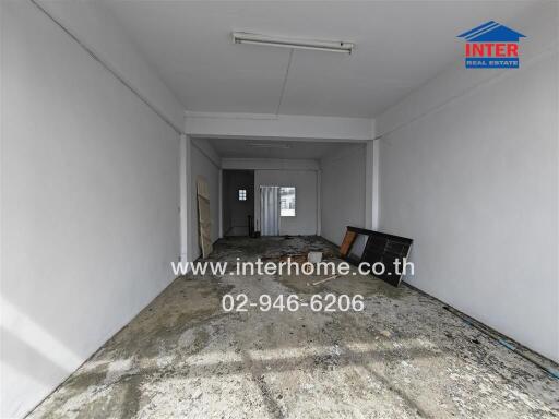 Unfinished room with bare concrete floor and INTER Real Estate logo