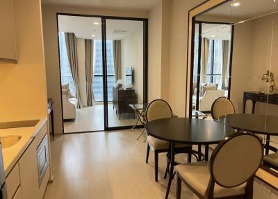 Modern dining area with round table, four chairs, kitchen and living room in background