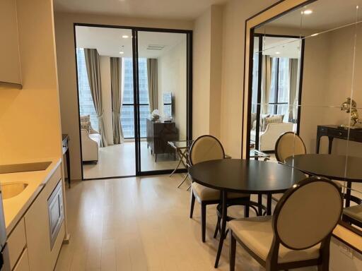 Modern dining area with round table, four chairs, kitchen and living room in background