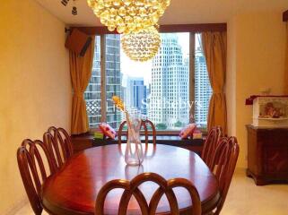 Dining room with wooden table and chairs, chandelier and view of city skyscrapers