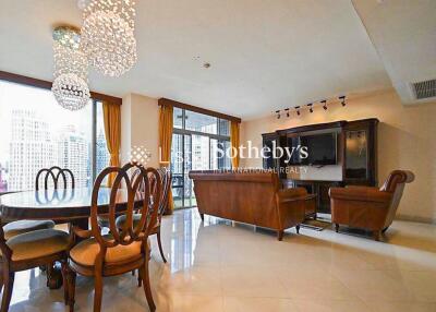 Spacious living room with chandeliers, dining area, and large windows