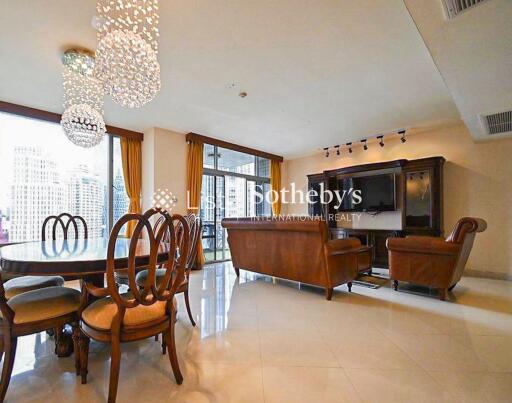 Spacious living room with chandeliers, dining area, and large windows