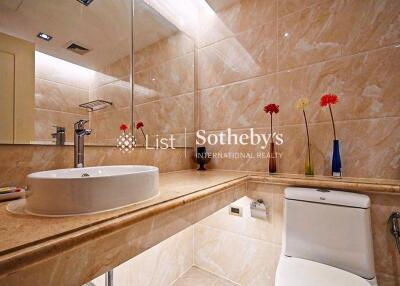 Modern bathroom with sink, toilet, large mirror, and decorative flowers