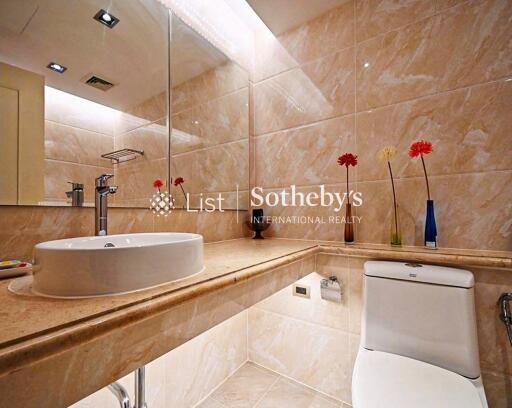 Modern bathroom with sink, toilet, large mirror, and decorative flowers