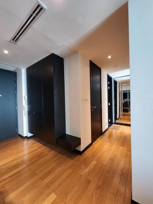 Modern hallway with wooden flooring and black doors