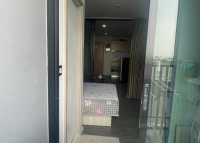 View through glass door into bedroom with bed, washer, and small balcony